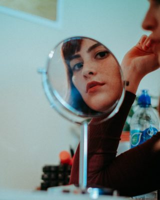 nainen katsoo peilin kautta kameraan