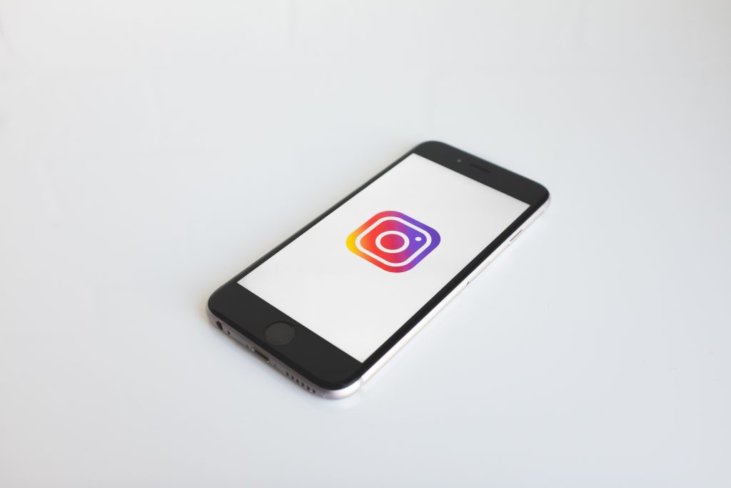 Valkoisella taustalla makaa puhelin, jossa on auki Instagramin logo.