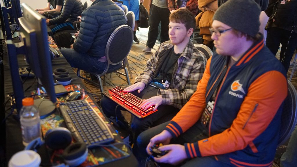 Kaksi henkilöä pelaa tietokoneen edessä vierekkäin.