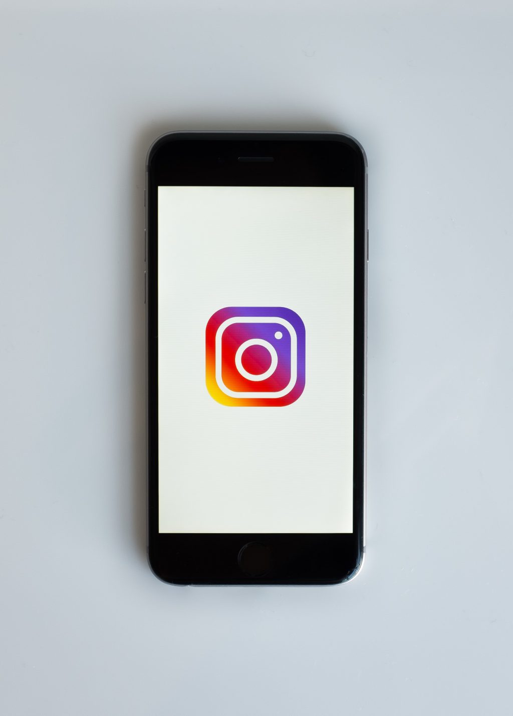 Musta puhelin valkoisella taustalla ja auki Instagramin värikäs logo.